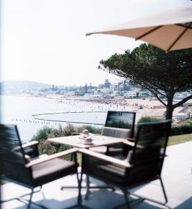 A beautiful patio with dark outdoor furniture overlooks a crowded beach in the background.