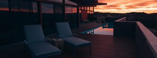 deck and lounge chairs in front of a sunset