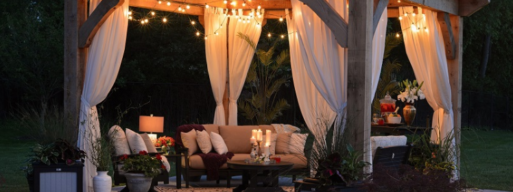 outdoor patio decorated with lights, curtains, candles, and stunning furniture