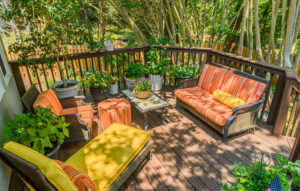 Home patio oasis with lots of green ery plants and comfortable wiker furniture.