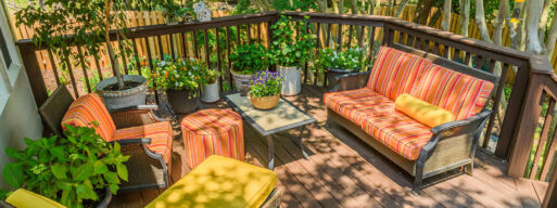 Home patio oasis with lots of green ery plants and comfortable wiker furniture.
